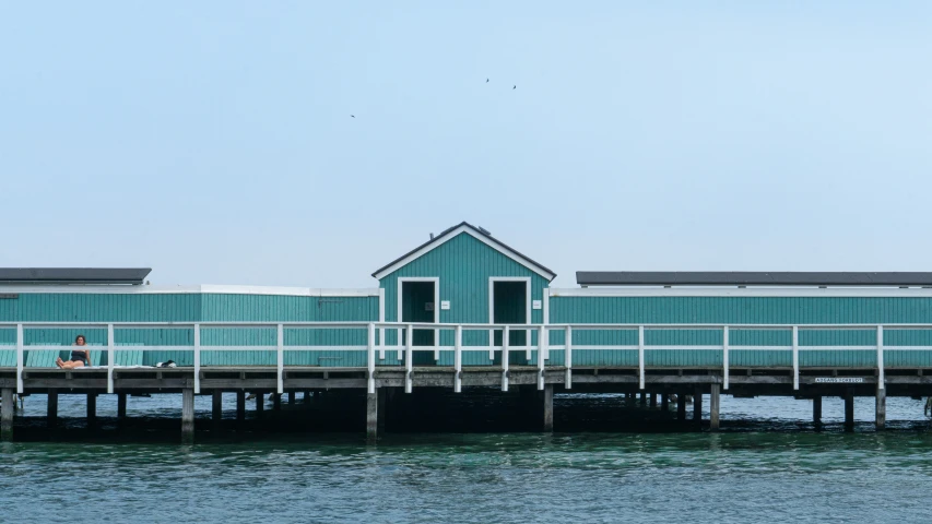 a pier with a small blue building on it's end