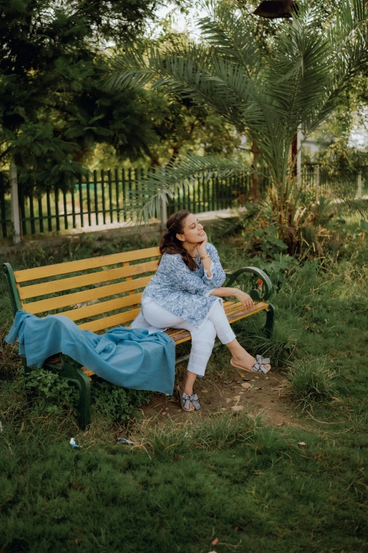 the woman sits on a bench in the park and smokes