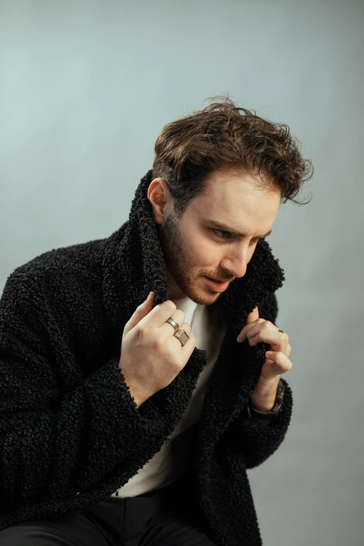 a man holding onto his coat, looking down
