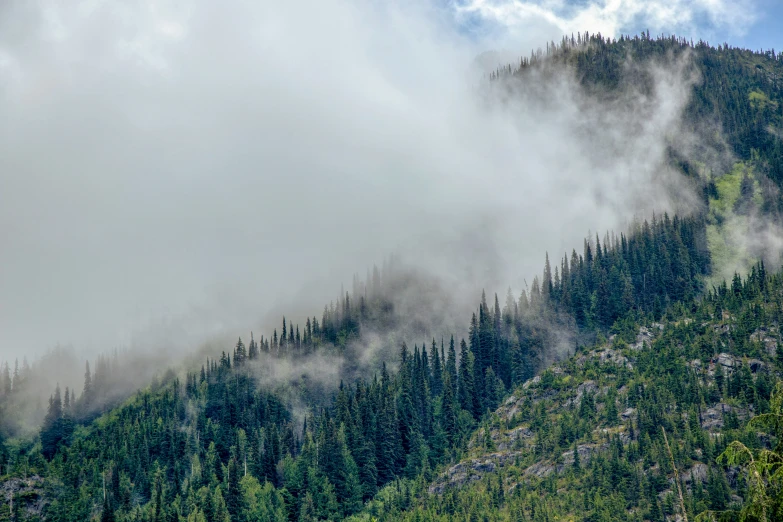 the clouds are rising from the top of the mountains