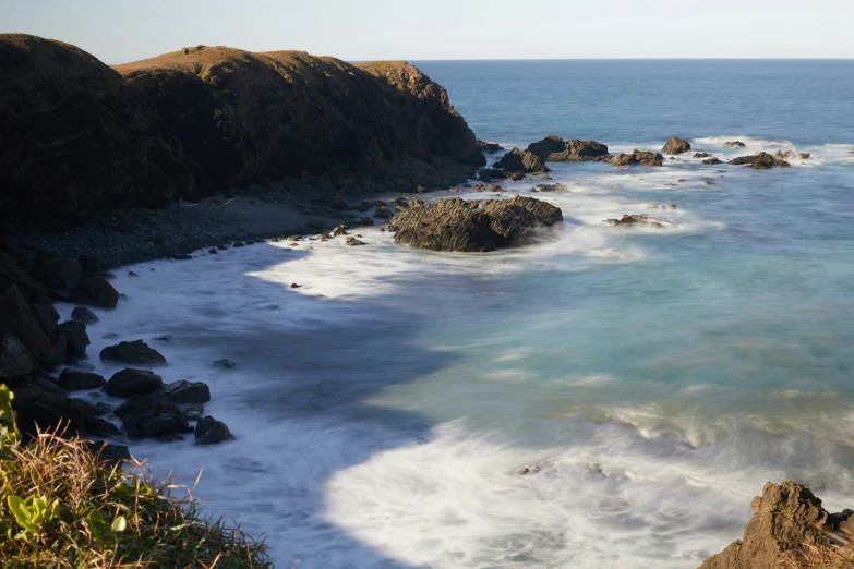 rocks and surf coming into the ocean near shore