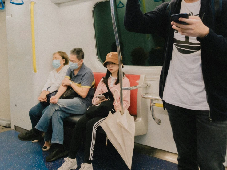 people sit on the subway with their umbrellas