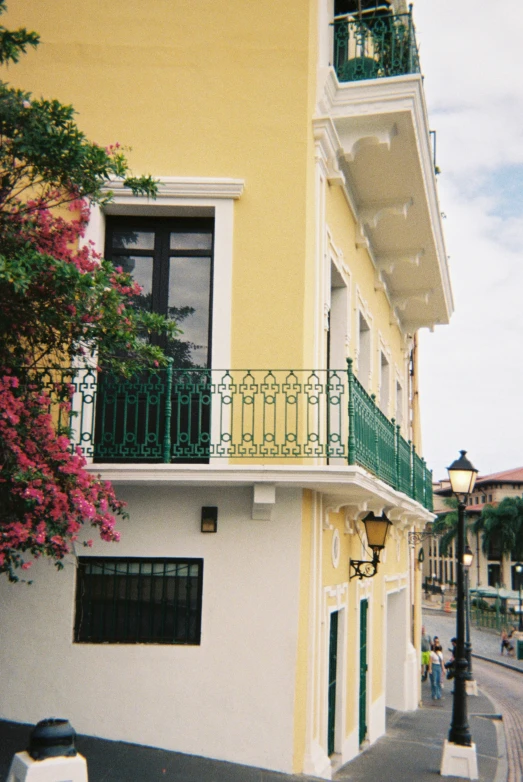 a clock in front of a yellow house with balconies