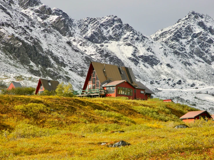 several homes on a hillside surrounded by snow capped mountains