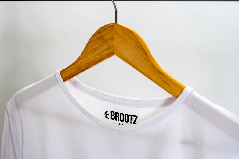 a white shirt hanging up on a wood hanger