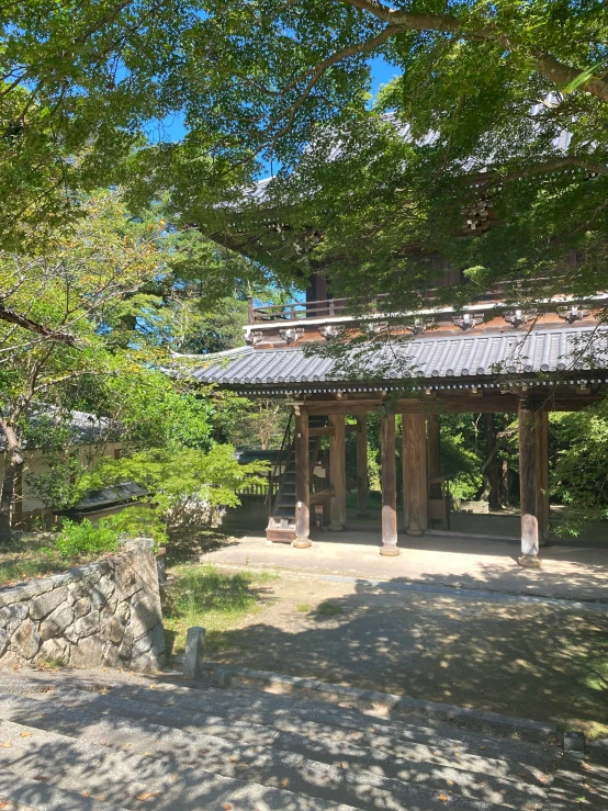 a pavilion with a bell on top surrounded by trees