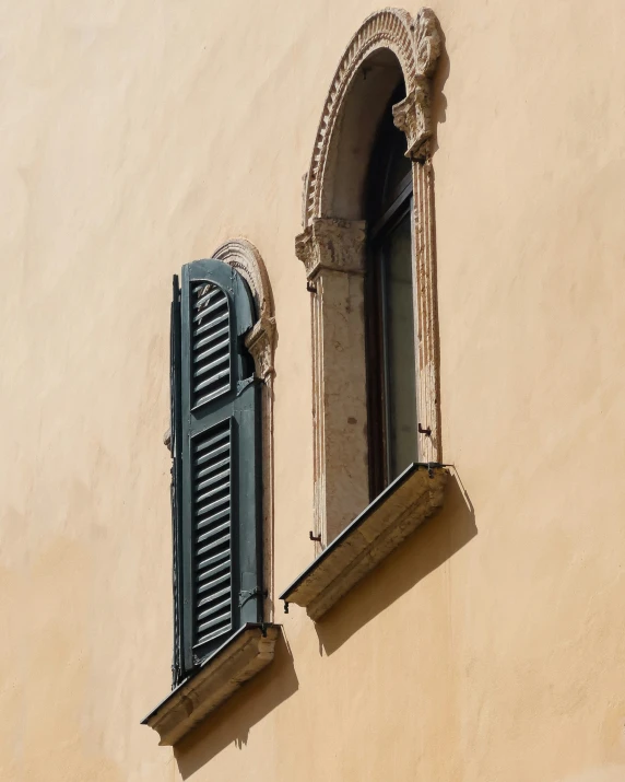 a window and a shutter on a beige building