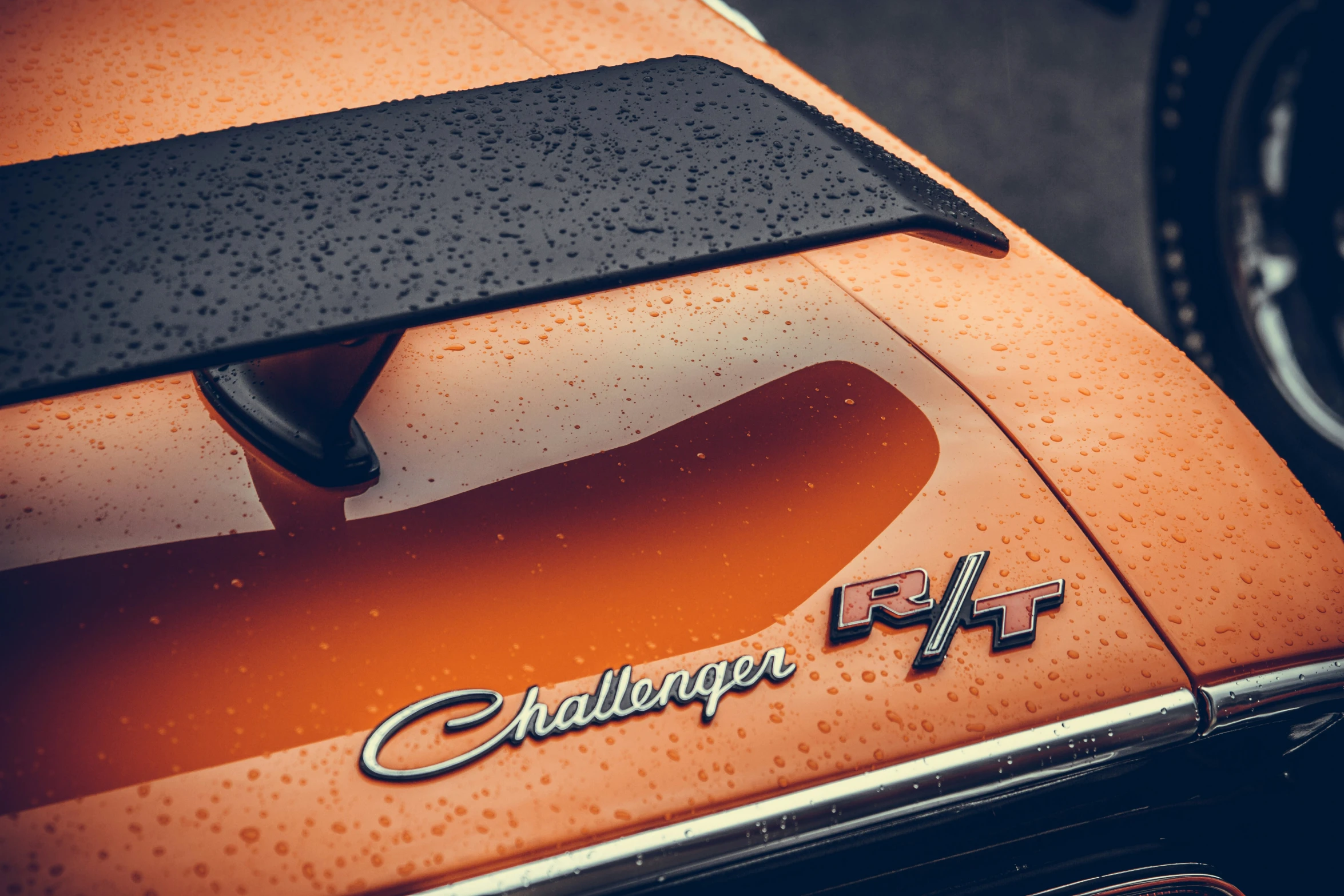 the tail end of an orange car with rain drops on it