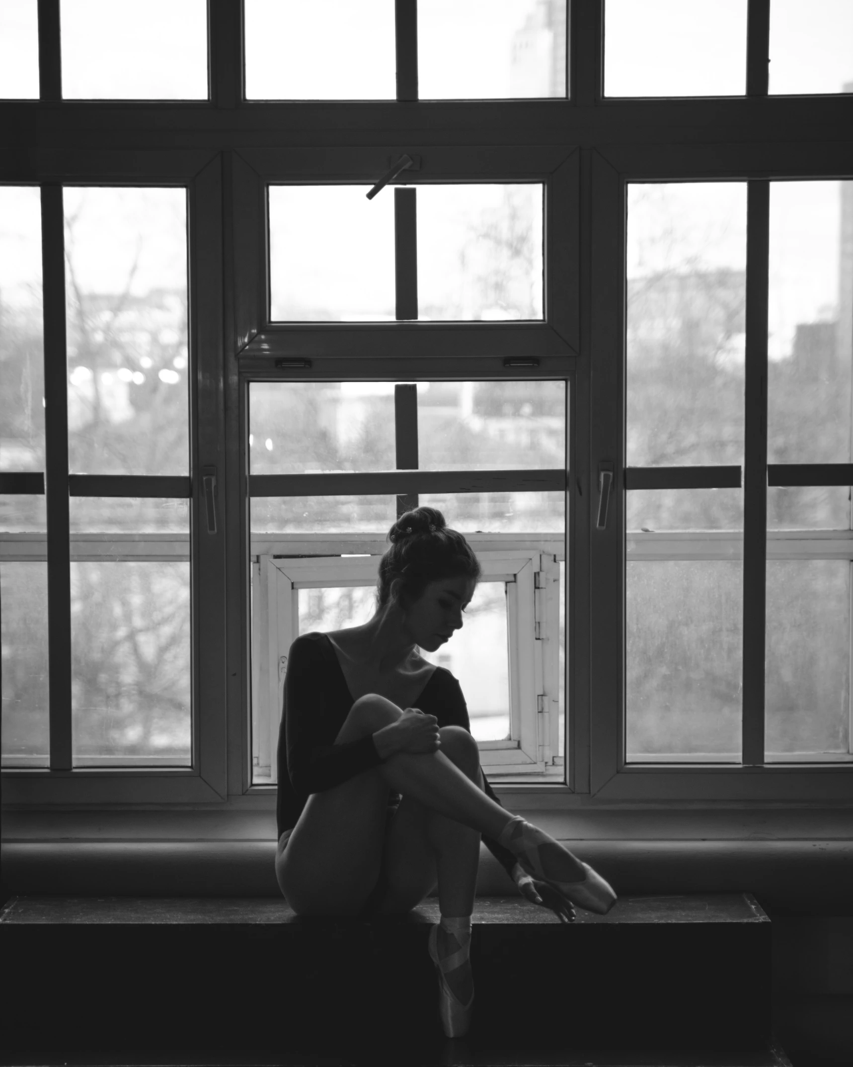 a woman sitting on the window ledge in front of a window