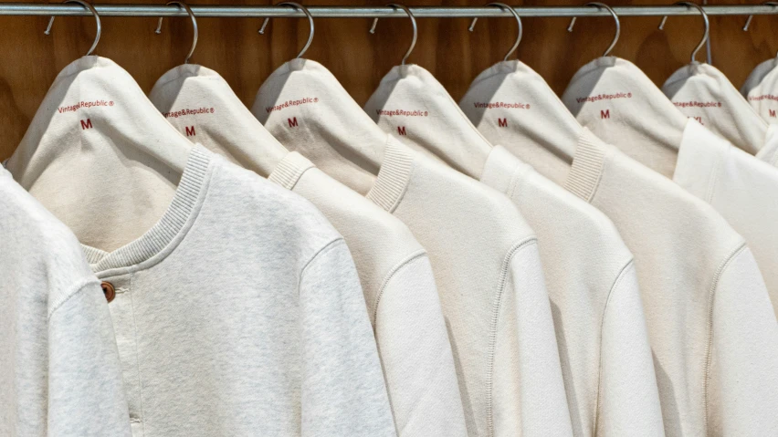 many white t shirts are hanging on a rack