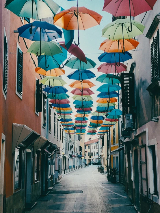 multiple open umbrellas hanging in the sky above a street