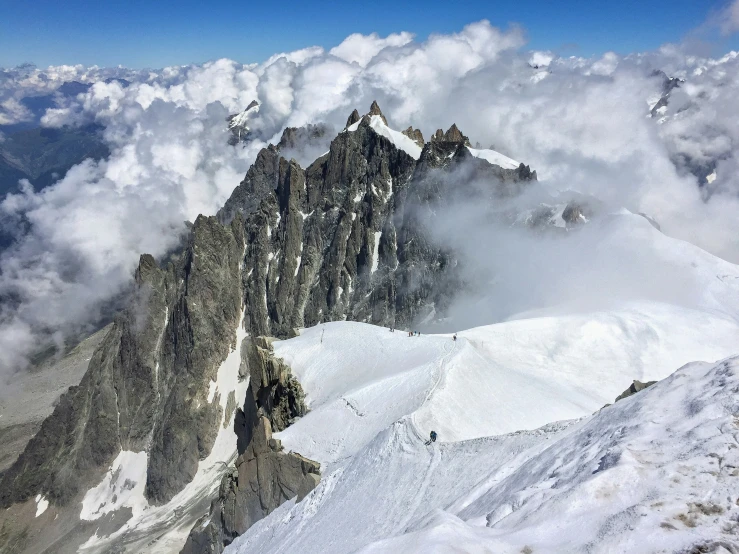 the tops of a mountain with snow and clouds