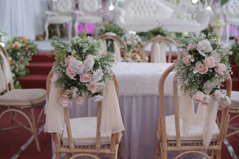 floral centerpieces are being displayed on chairs in a decorated banquet hall