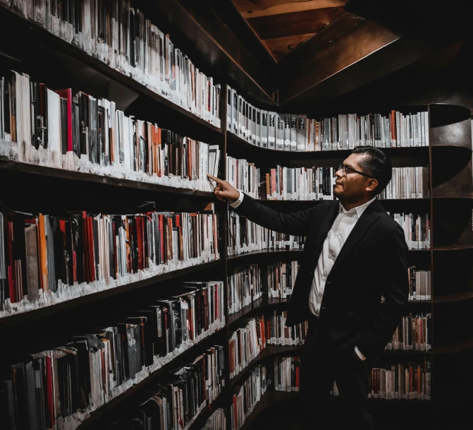 a man is pointing at shelves with books