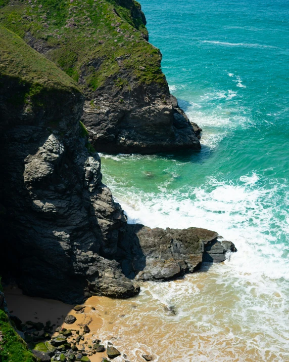 a rocky beach with a green steeple and body of water