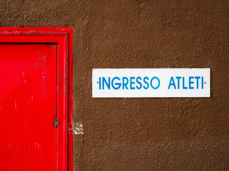 there is a red door and brown wall with a sign above it that says ingressso aleti
