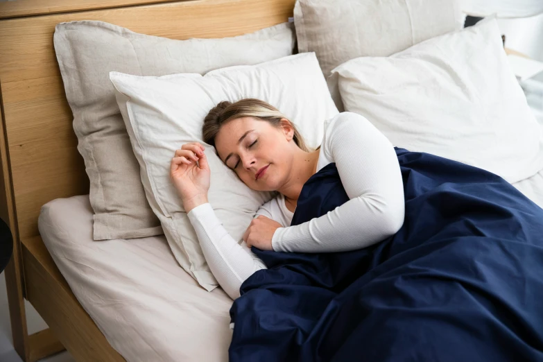 a woman laying in bed with her hands resting on a pillow