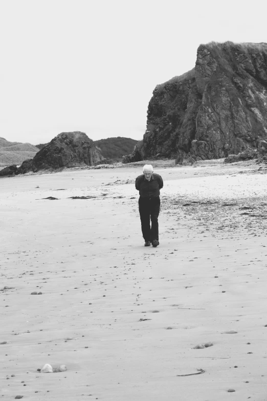 the person walks on a beach and looks out at some water