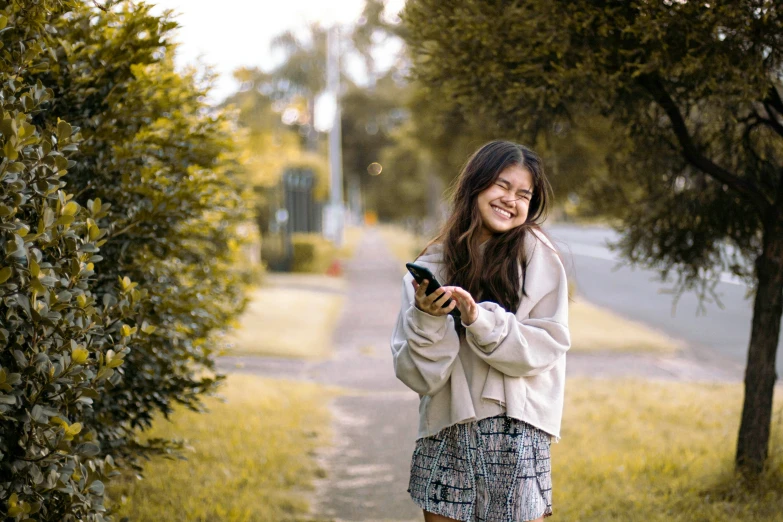 a girl standing in the street looking at her cell phone