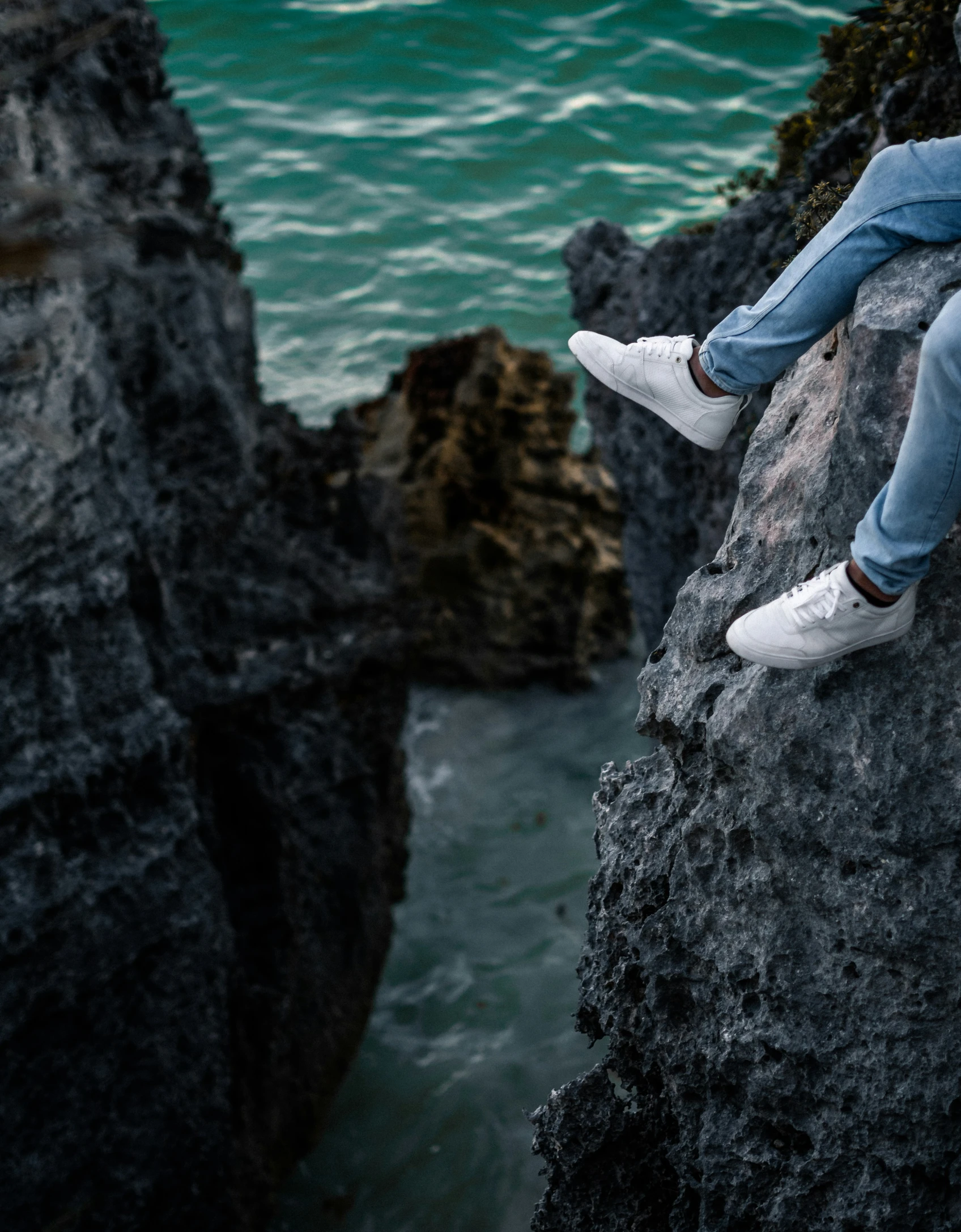 man sitting on a rock next to ocean