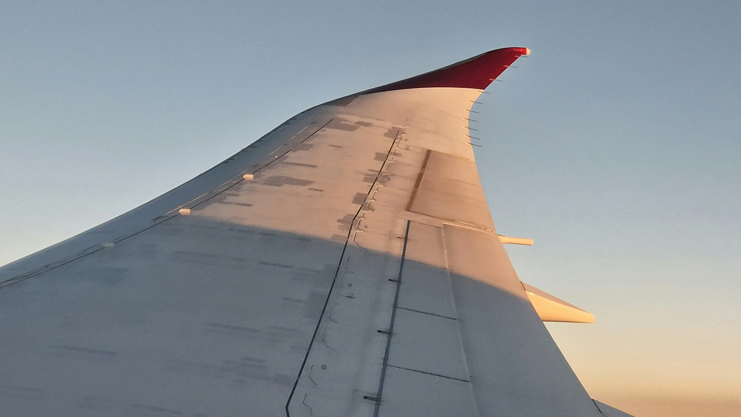 the tip of a plane's wing at sunrise