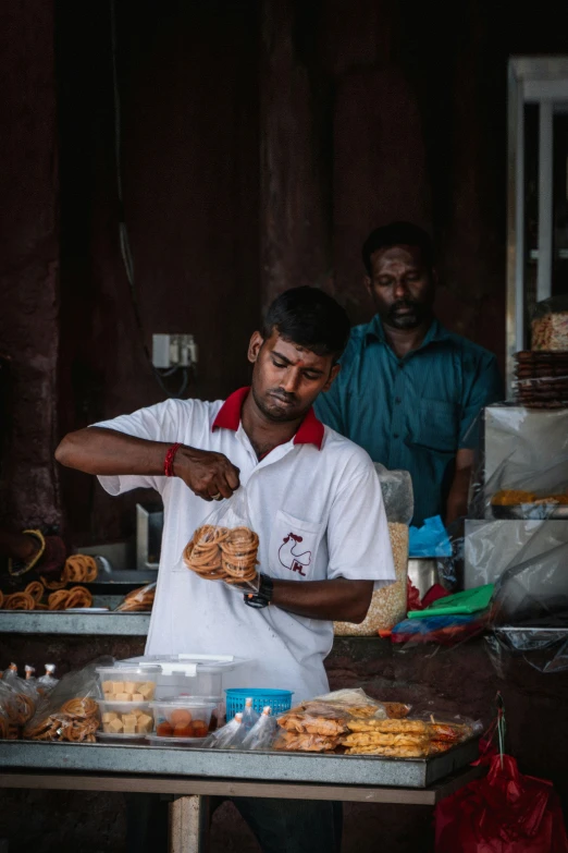 man in white apron preparing food at outdoor stand