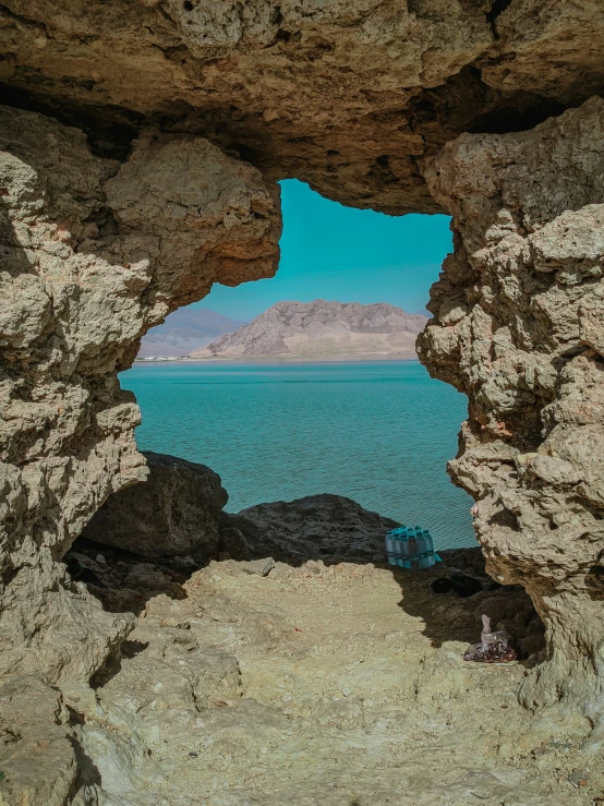 a small cave sits in front of a blue ocean