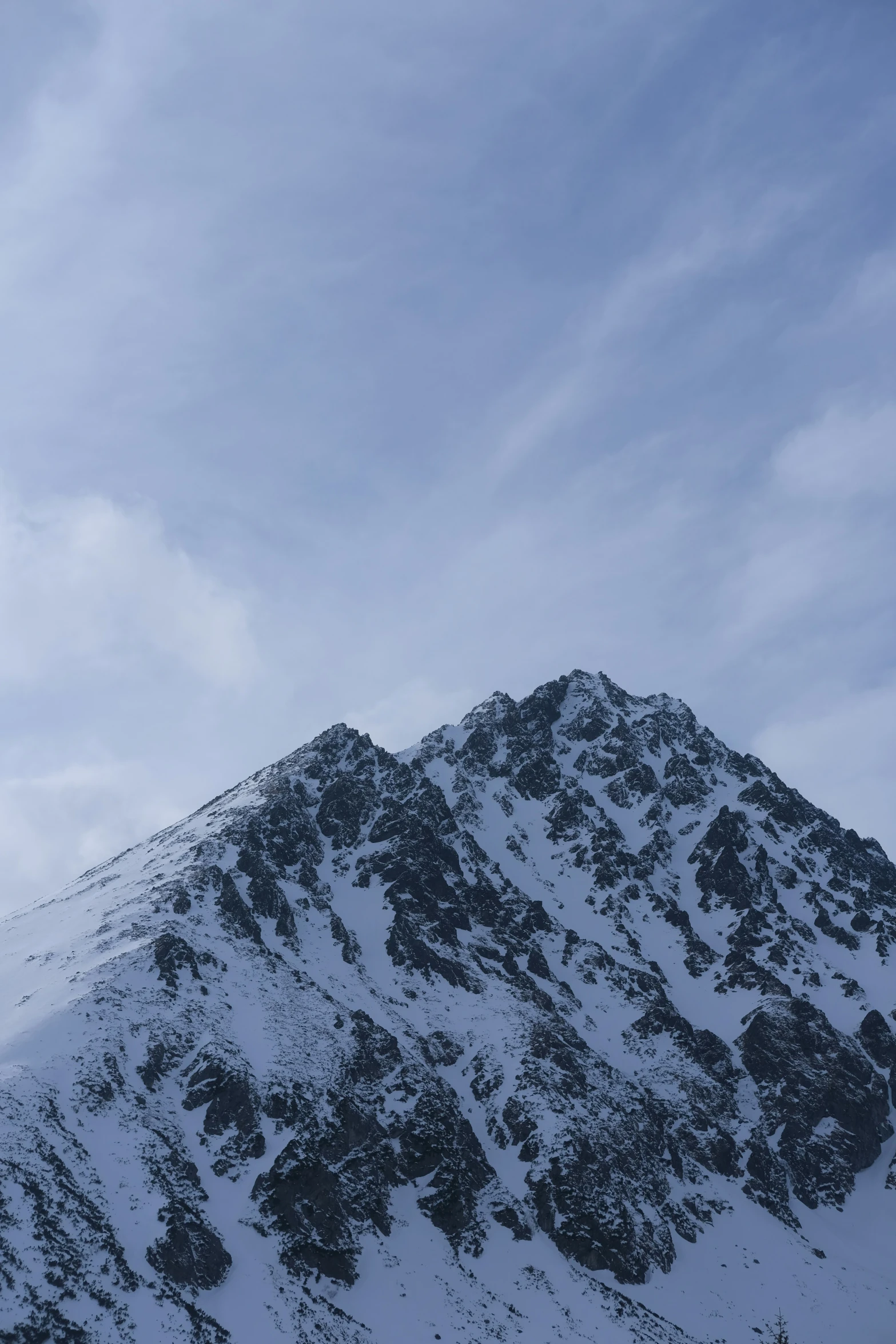 a snow covered mountain with sky background and one plane flying over it