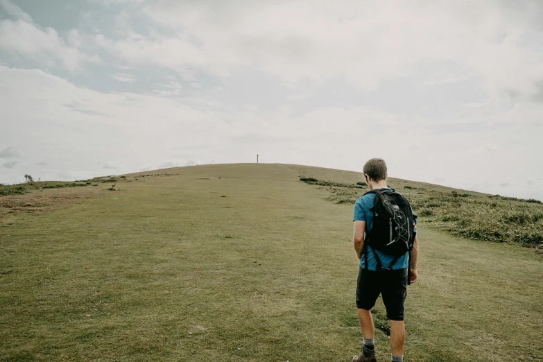 the man walks up a hill to watch the sky