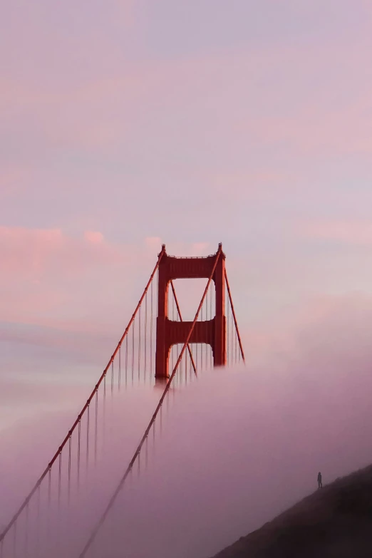 the red golden gate bridge is in thick clouds