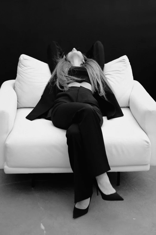 a woman laying down on a couch in black and white