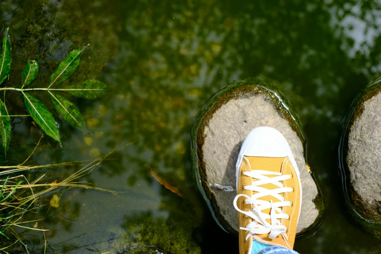 someone's sneakers are on some rocks by water