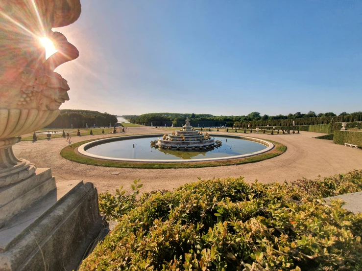 the sun shines on the garden, with an odd fountain