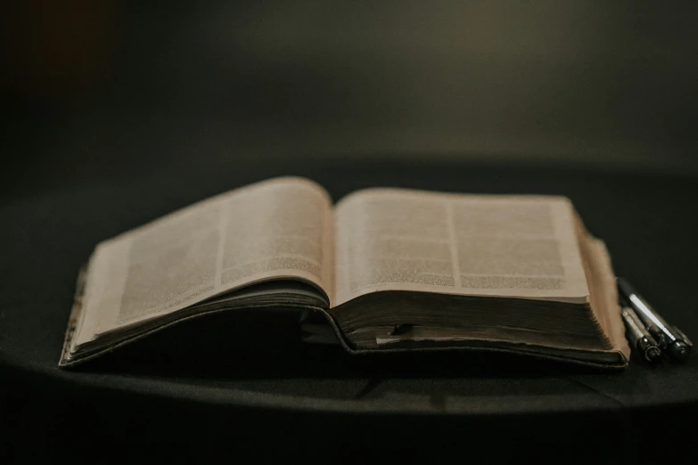 an open book on a table with a pen