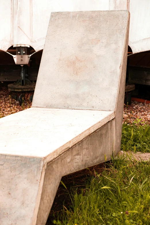 concrete bench sitting in a grassy area next to a dumpster