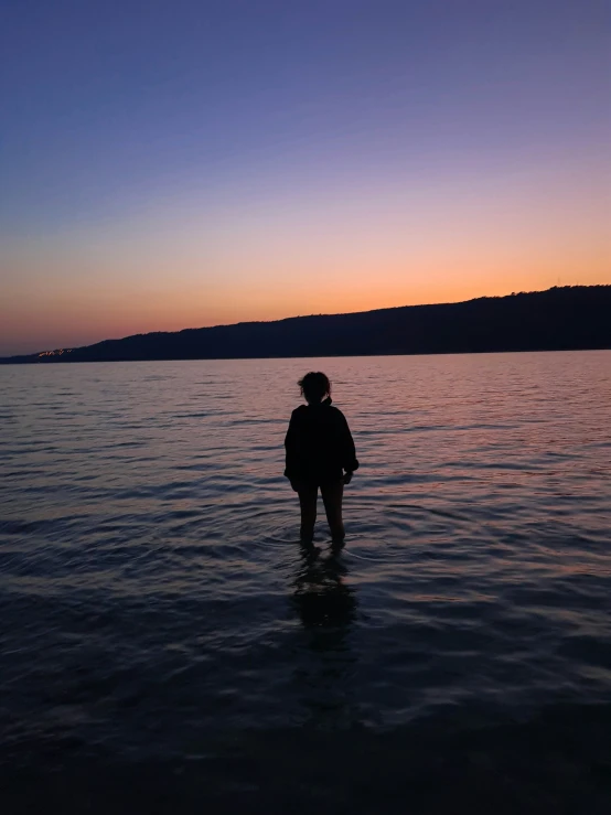 a person standing on the water in front of some mountains