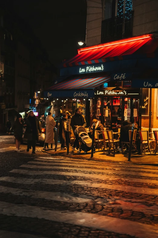 people gather outside a large cafe at night