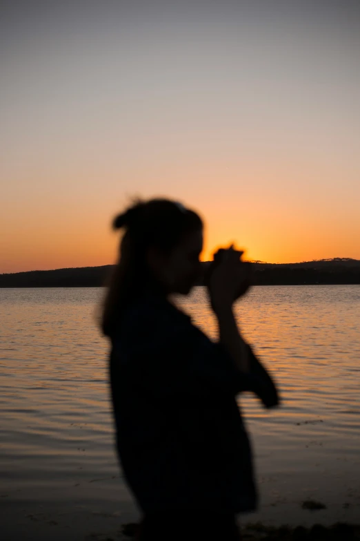 the silhouette of a person on a beach at sunset