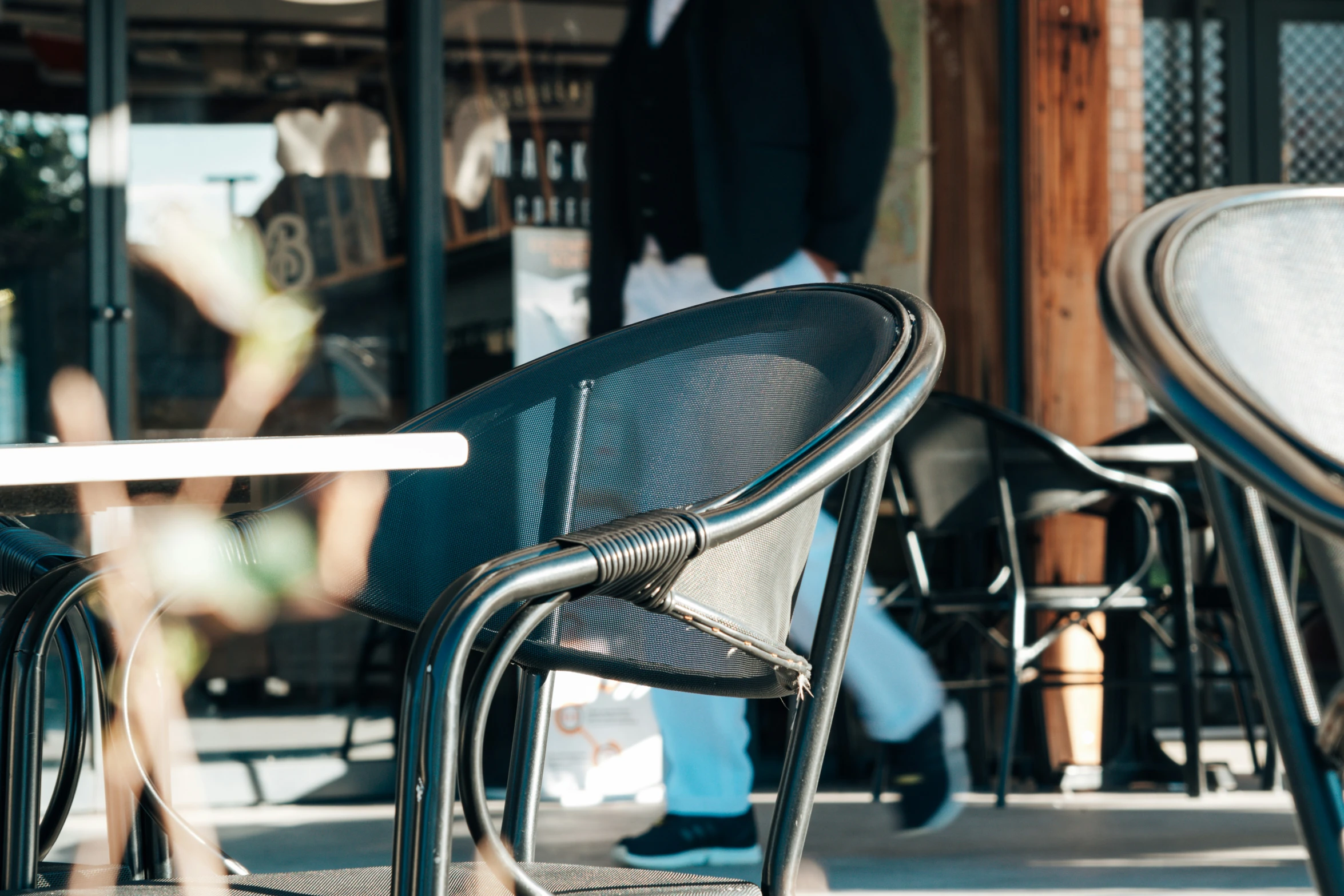 a man walking in front of an outdoor restaurant with patio furniture