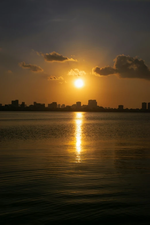 the sun shining brightly on the ocean and buildings in the distance