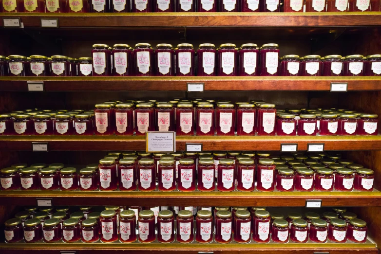 a display filled with lots of jars of jam on wooden shelves