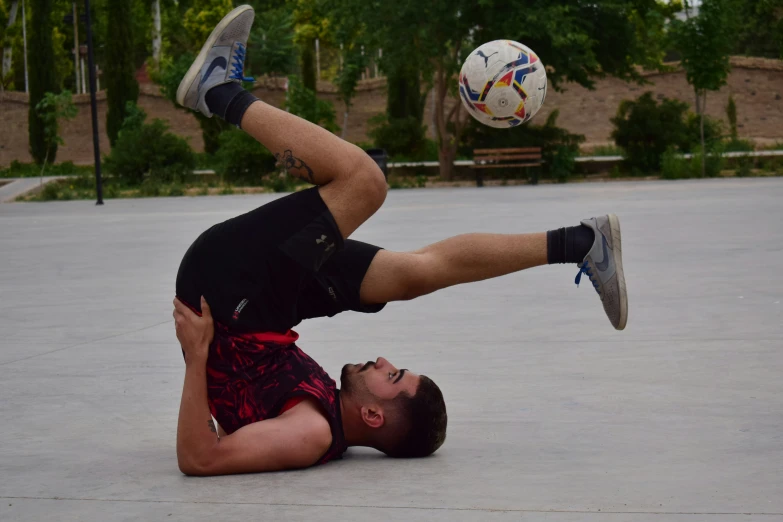 a man is laying on the ground and has his legs in the air as he plays soccer