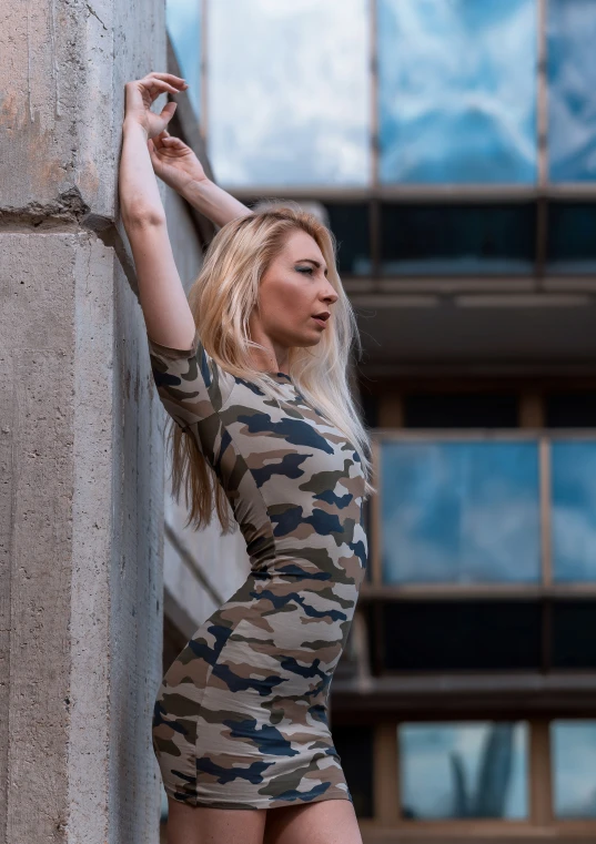 a blond woman with her arms around the back of a building