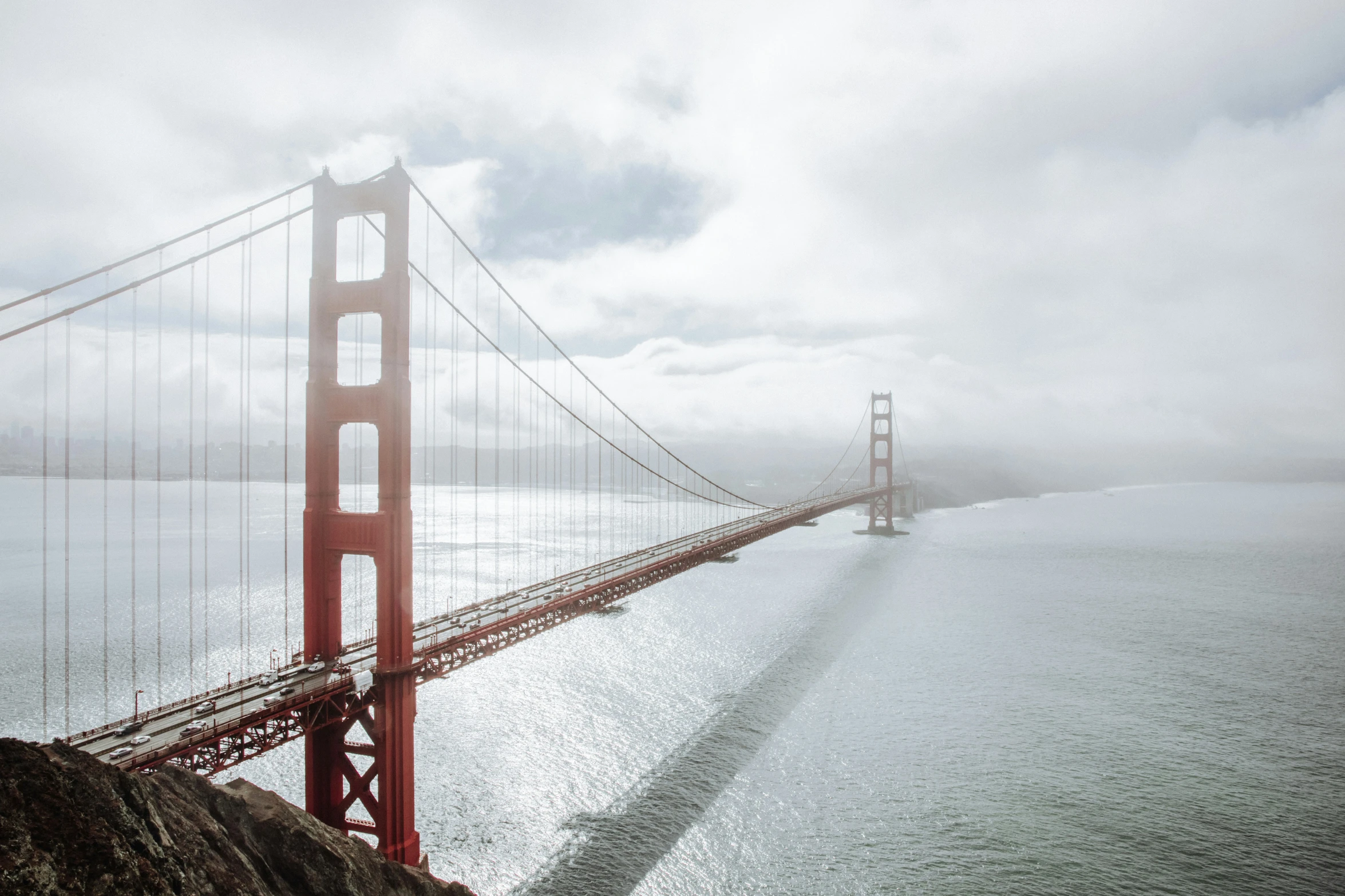 a very long bridge crossing the water in front of some hills