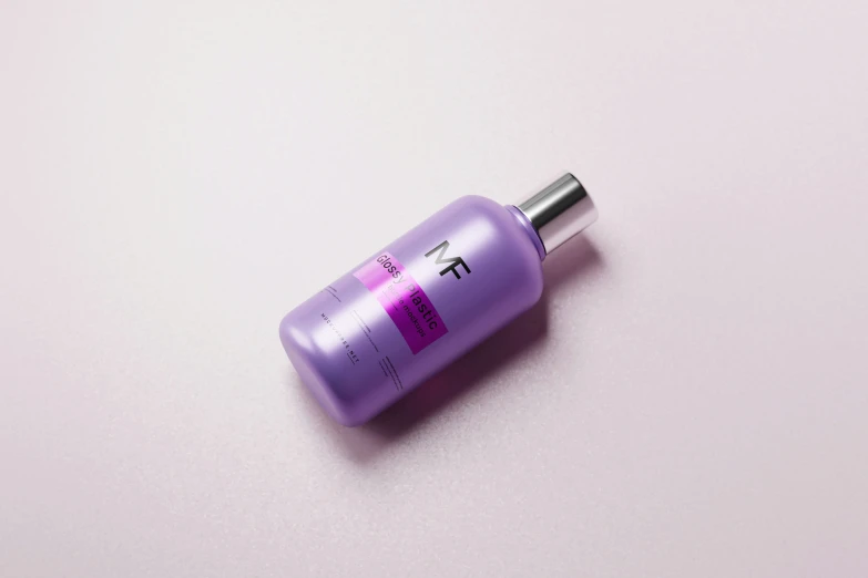 a bottle of purple tinted cosmetic product sitting on top of a table