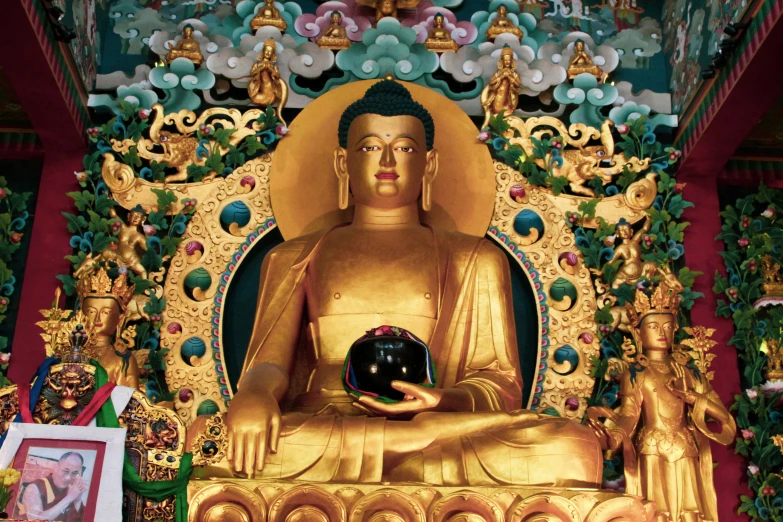 a golden buddha statue holding a black ball in front of some decorations