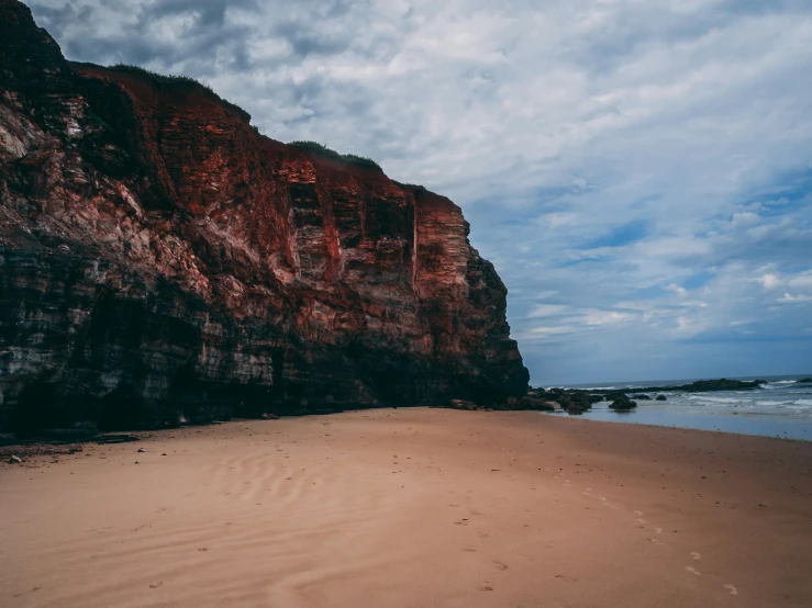 the sandy beach has a large rock formation on it