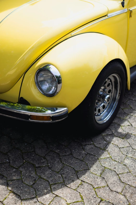 a yellow car that is sitting on a cement ground