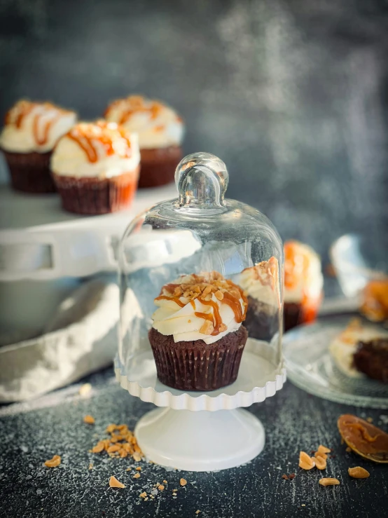 a cup cake under a glass covered cover on top of a cake stand