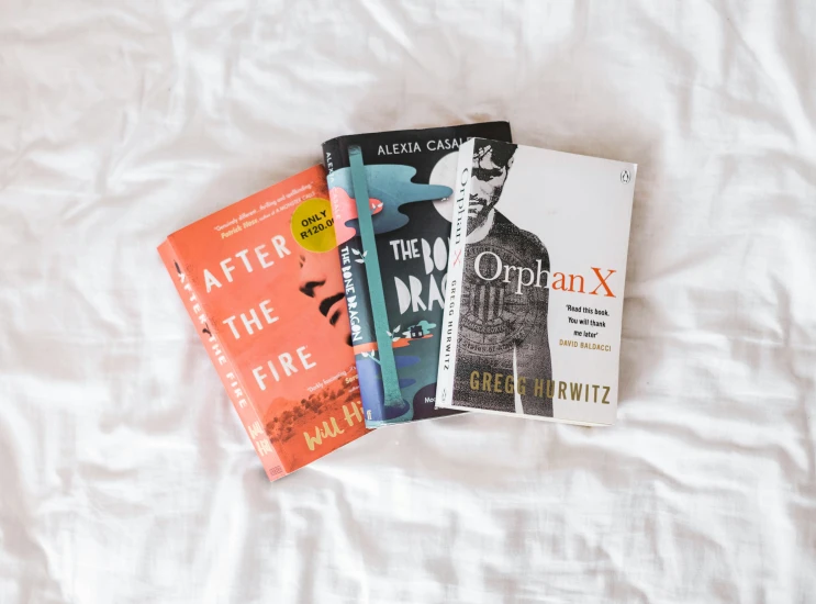 four novels on the cover of a white bed